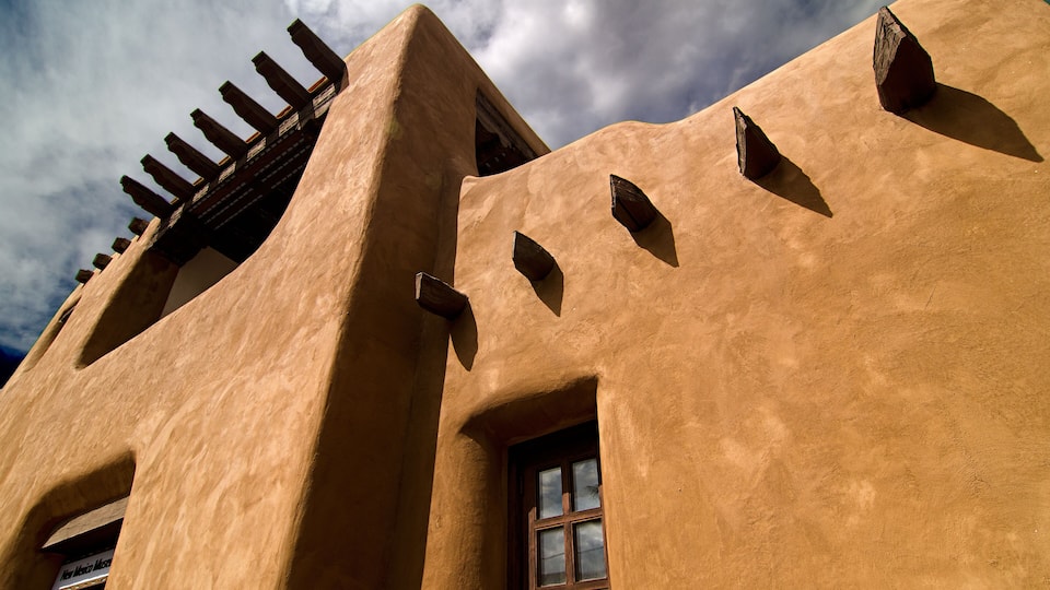 A building with a unique architectural style, featuring a sloped roof and a wooden balcony.
