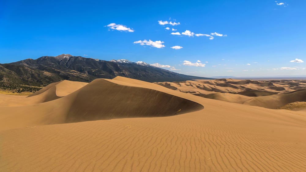 Great Sand Dunes - A panoramic view at top of Great Sand Dunes, looking from east towards north-west, on a sunny but windy Spring evening. Great Sand Dunes National Park & Preserve, Colorado, USA.