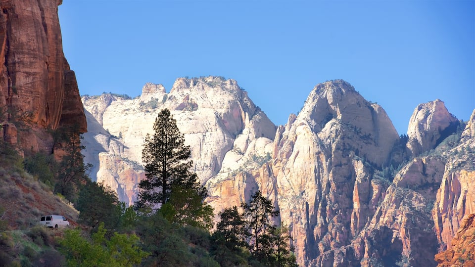 A canyon with prominent rock formations and a white van parked on a slope.