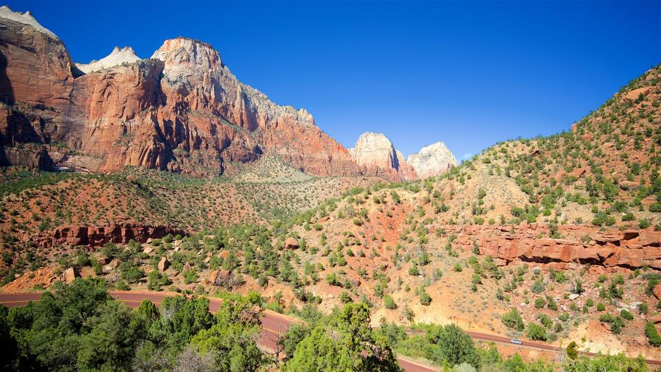 A mountainous landscape with red rock formations and green vegetation.