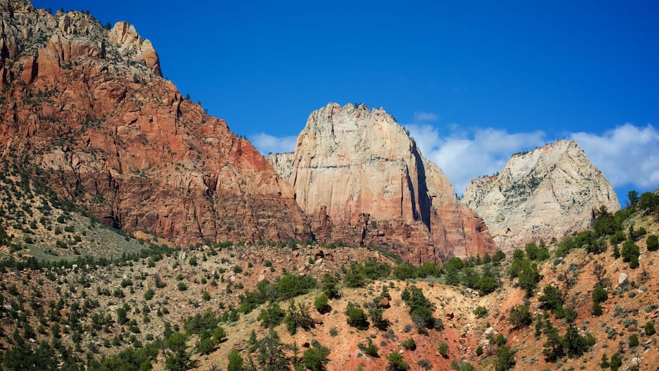 A rugged mountain landscape with prominent red and white rock formations under a clear blue sky.