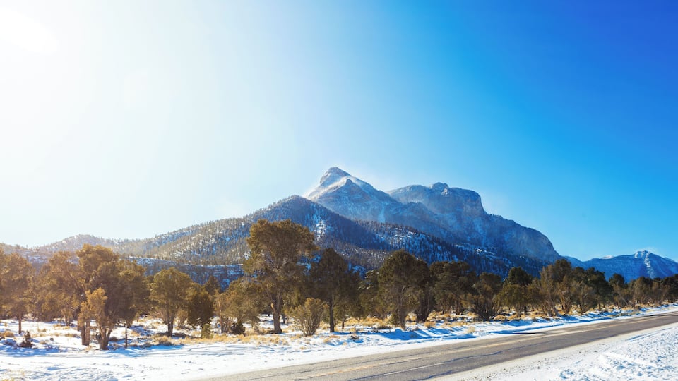 A snow-covered road with mountains in the background.
