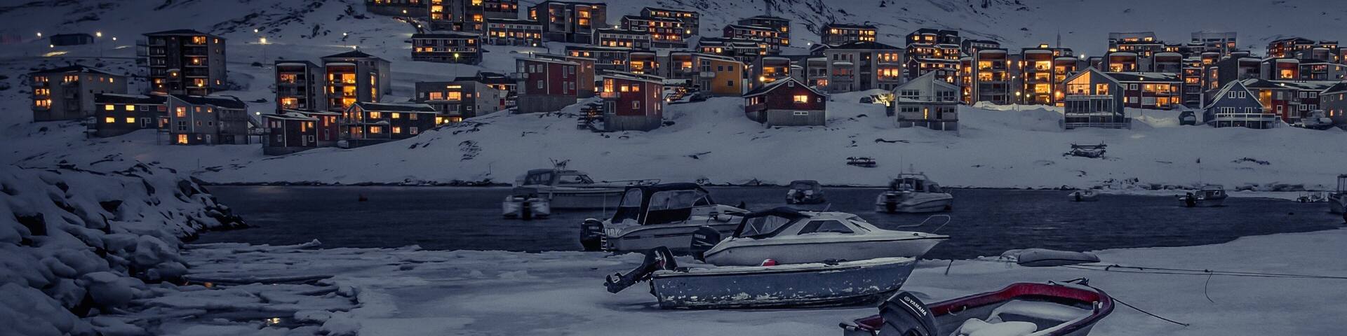 Nuuk mostrando montañas, botes y una pequeña ciudad o aldea