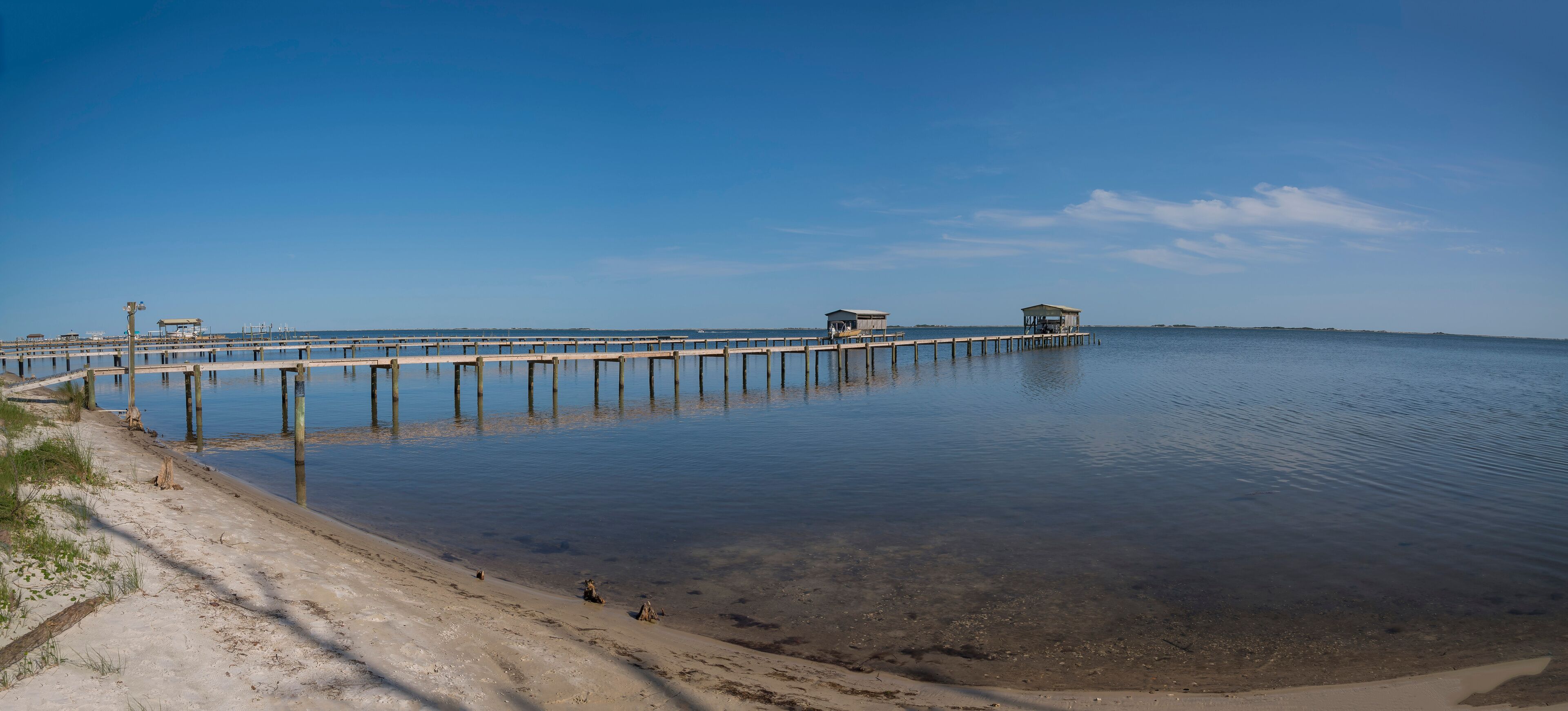A pier extending into calm waters with clear skies.