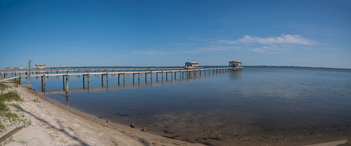 A pier extending into calm waters with clear skies.