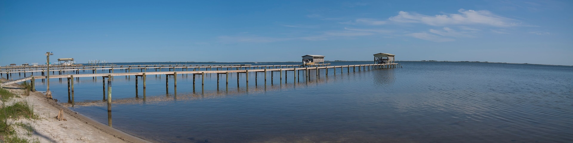 A pier extending into calm waters with clear skies.
