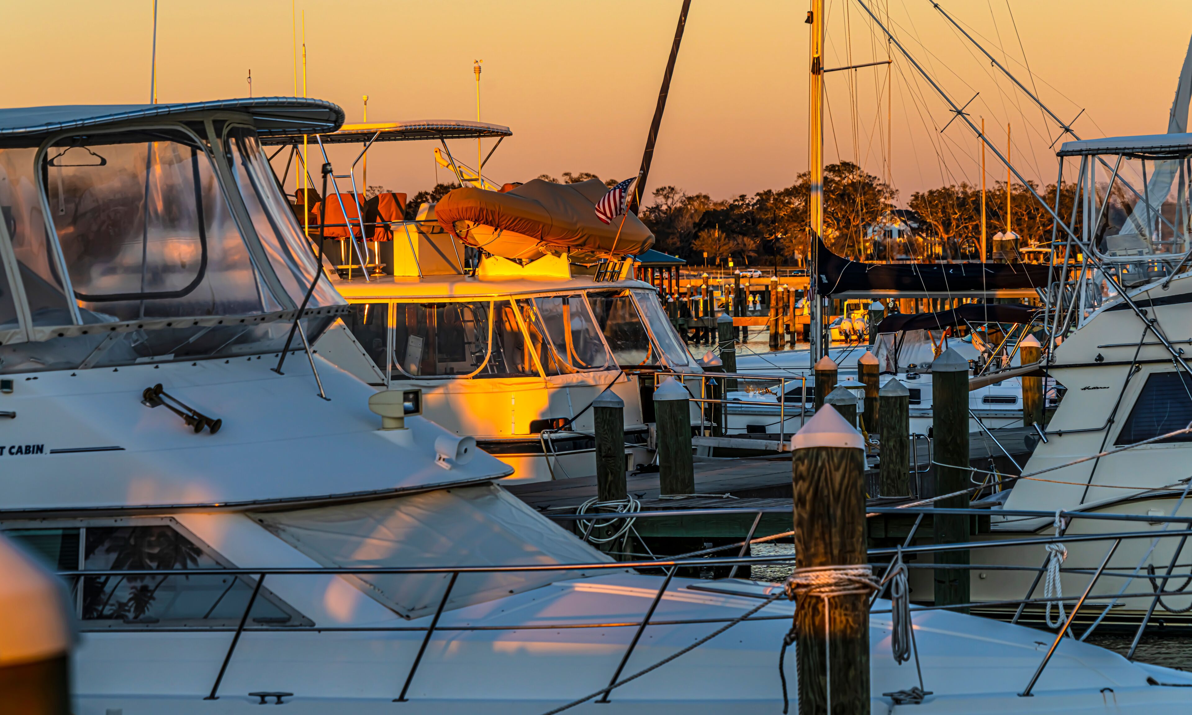 A marina with various boats docked, including a cabin boat and sailboats.