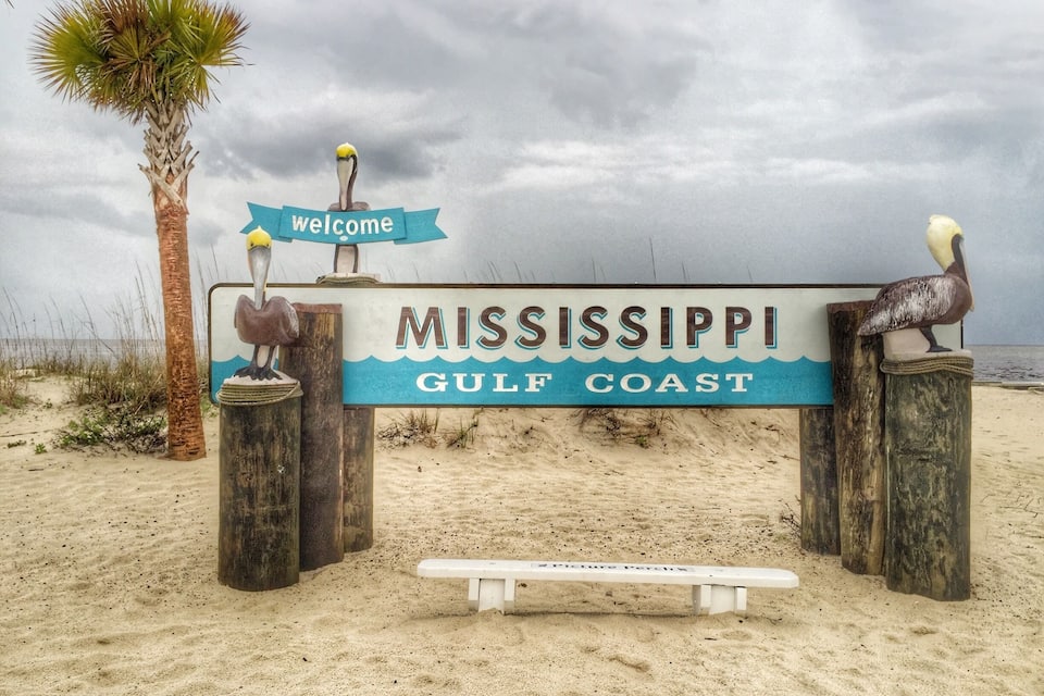 A welcome sign for Mississippi Gulf Coast with a pelican sculpture.