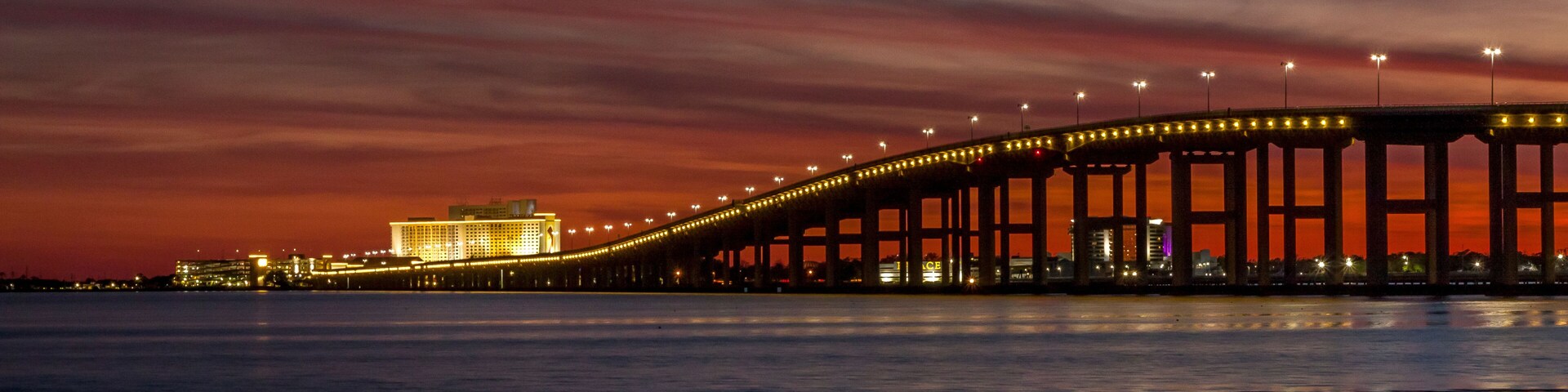 Un puente al atardecer, con luces reflejándose en el agua.