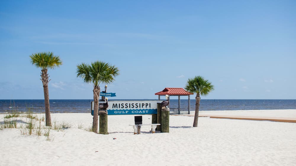 Beautiful summer landscape by the ocean with white sand and clear blue skies, palm trees and a gazebo on a summer sunny day.Ken Combs Pier, Gulfport, Mississippi, USA - 7-4-2019