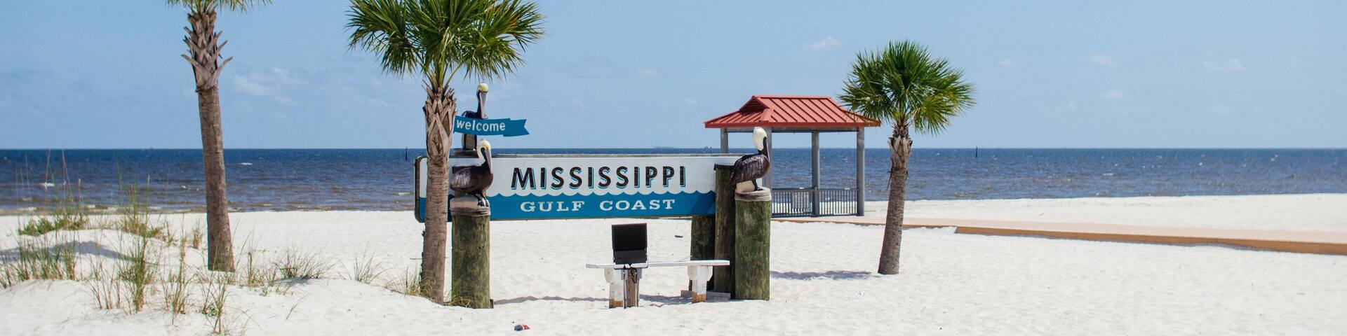 Beautiful summer landscape by the ocean with white sand and clear blue skies, palm trees and a gazebo on a summer sunny day.Ken Combs Pier, Gulfport, Mississippi, USA - 7-4-2019