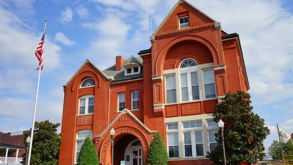 A red brick building with arched windows and a flagpole with an American flag.