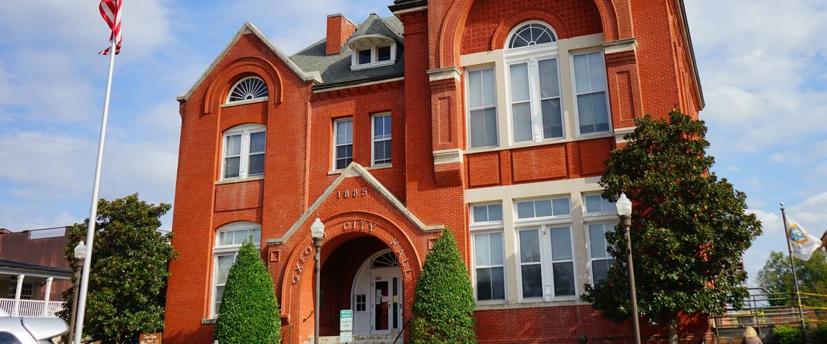 A red brick building with arched windows and a flagpole with an American flag.
