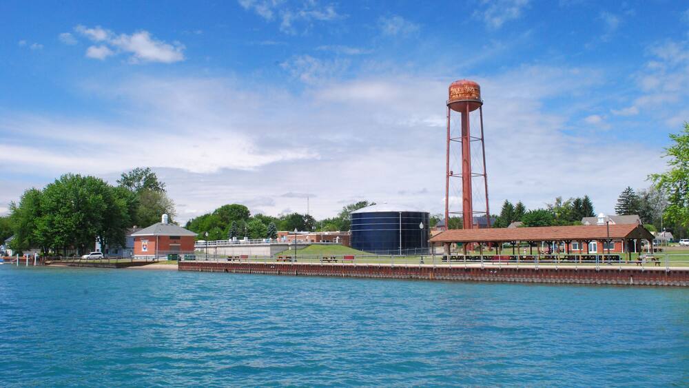Ein Wasserturm, ein großer zylindrischer Tank und ein rotes Gebäude am Wasser.