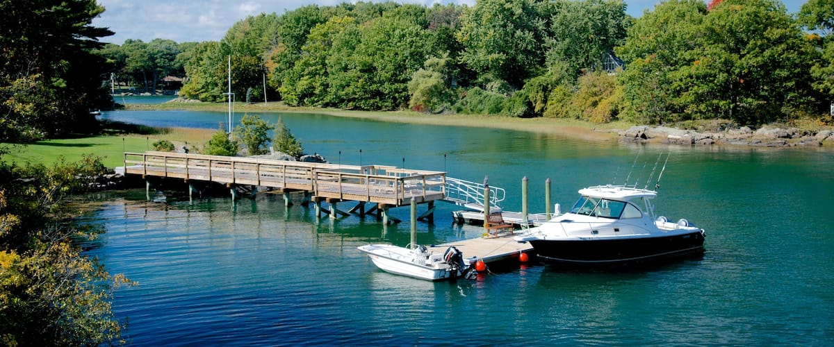 A calm river with a wooden dock and two boats moored at the pier.