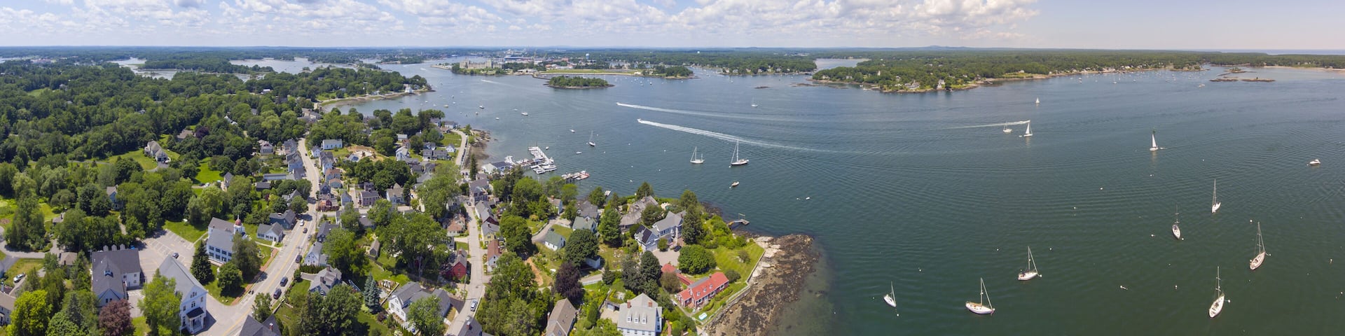 A coastal town with a marina, boats, and lush greenery.
