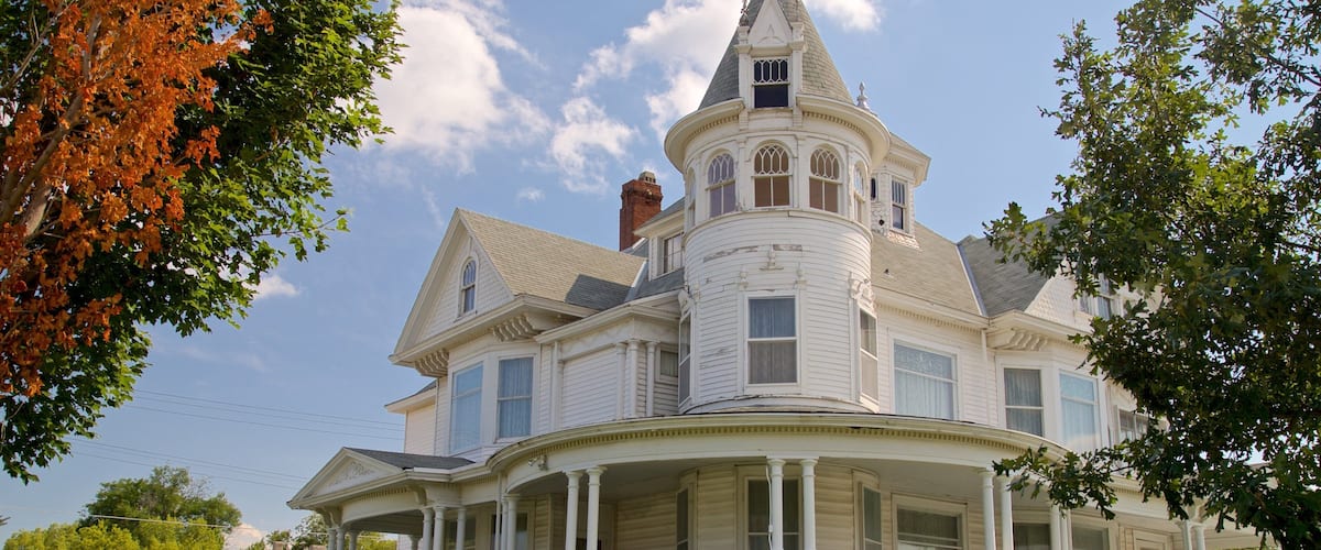A large, white Victorian-style house with a turret and wrap-around porch.