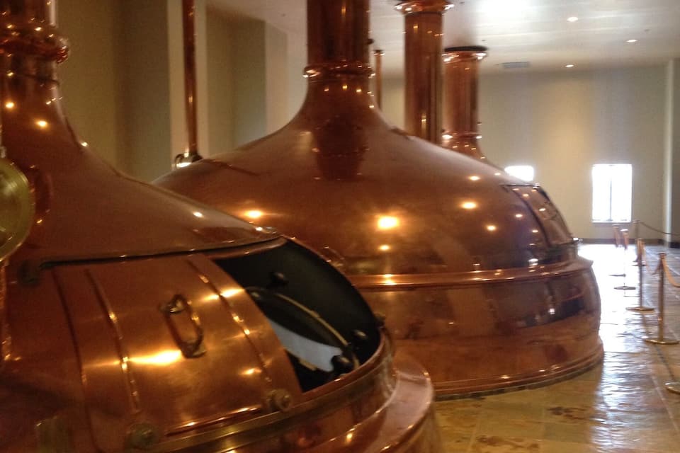 De grandes colonnes de distillation en cuivre à l’intérieur d’un bâtiment.