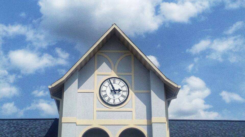 A clock tower with a triangular roof and a clock face.