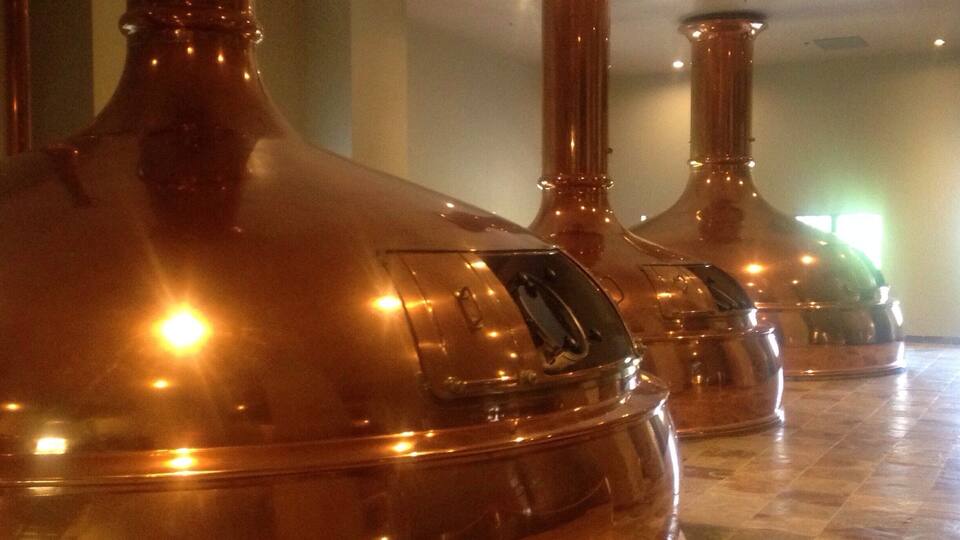 Copper distilling equipment in a clean, well-lit room with tiled flooring.