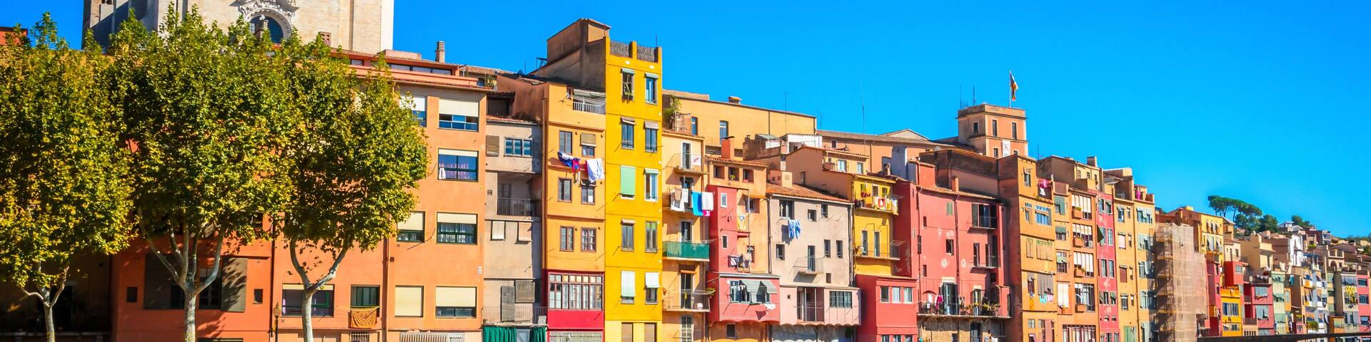 A waterfront with colorful buildings, a stone wall, and a tower.