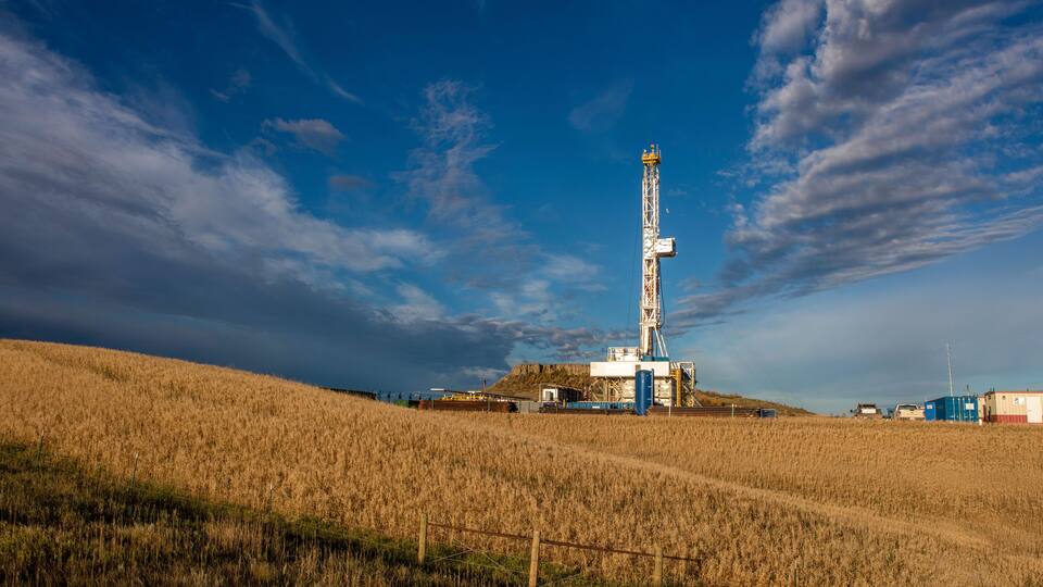 A drilling tower in a field with a clear sky.