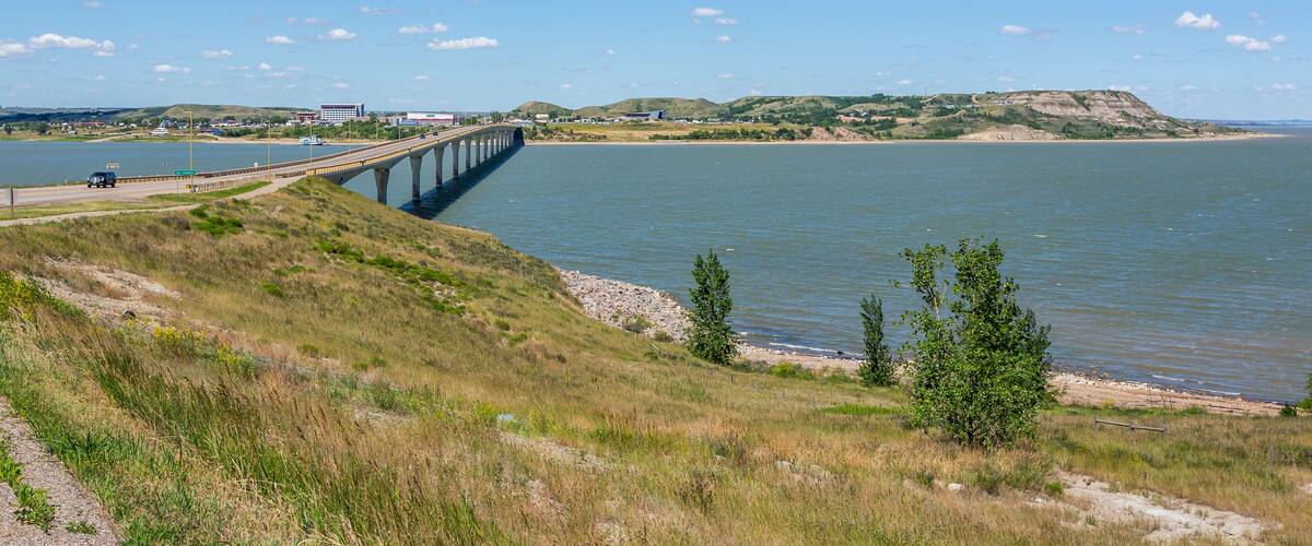Un puente sobre un río, colinas cubiertas de hierba y un edificio distante.