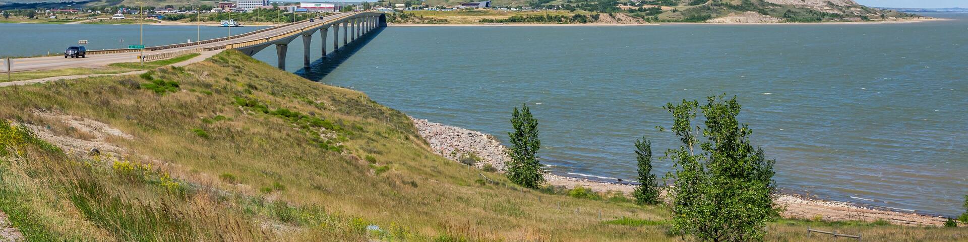 A bridge over a river, grassy hills, and a distant building.