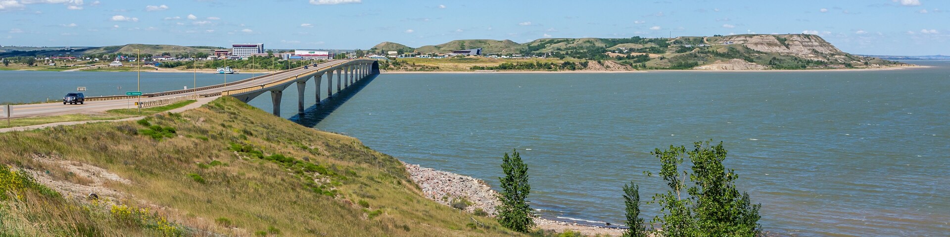 Un puente sobre un río, colinas cubiertas de hierba y un edificio distante.