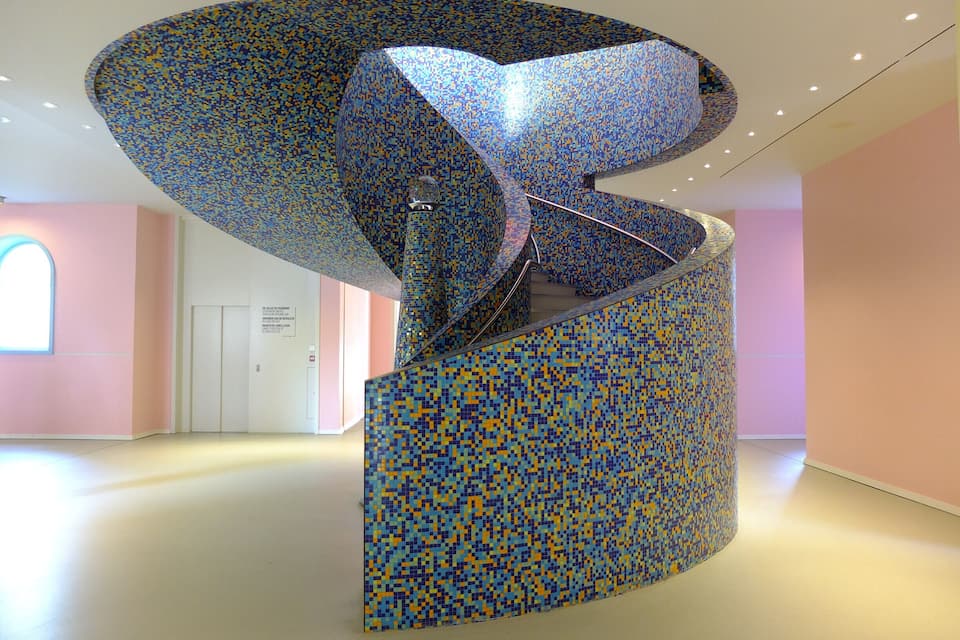 A spiral staircase with mosaic tile walls in a modern building.