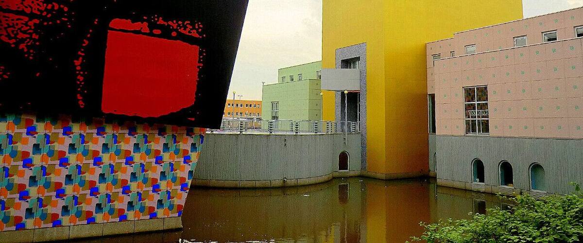 Un edificio moderno con fachada amarilla y una estructura roja grande al frente.