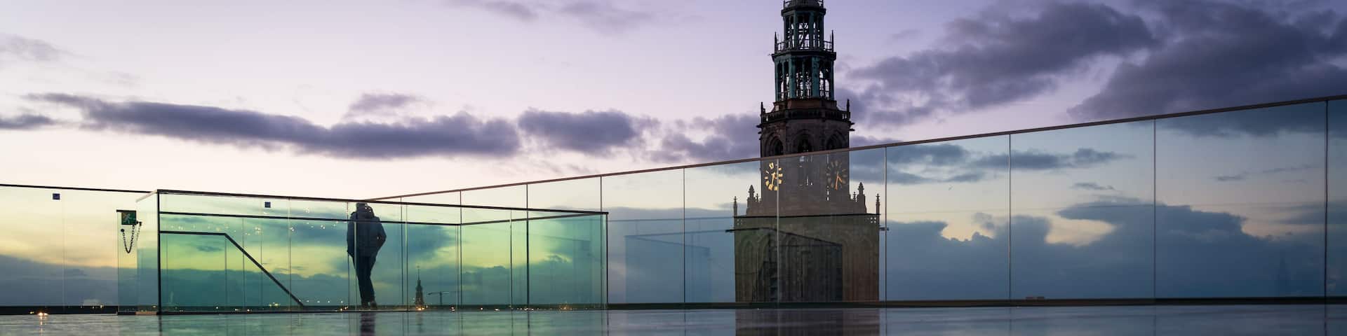 A person walking on a reflective surface with a historic tower in the background.