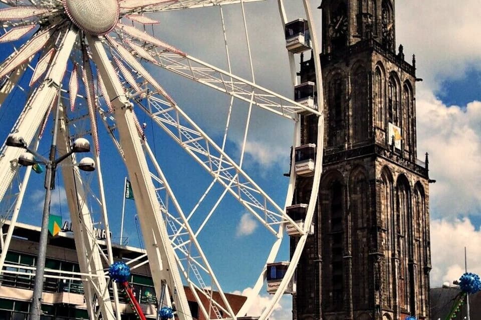 A Ferris wheel, a tall clock tower, and a carnival with rides.
