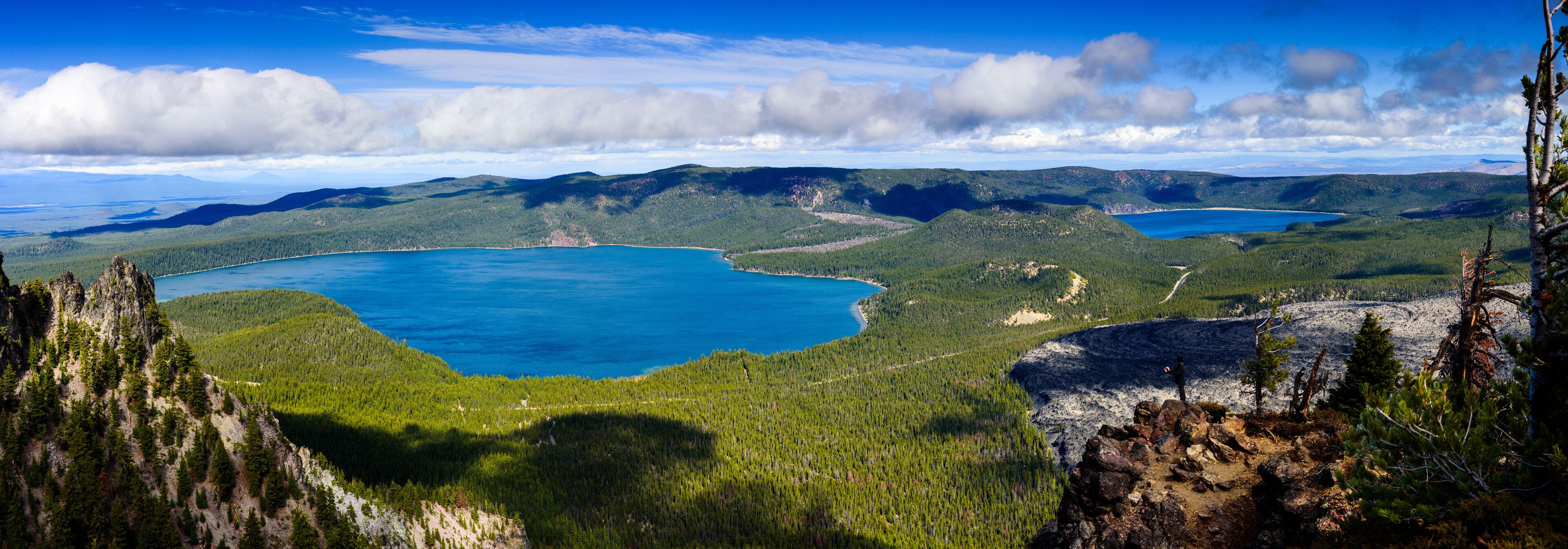 A mountainous landscape with two large turquoise lakes surrounded by dense forests.