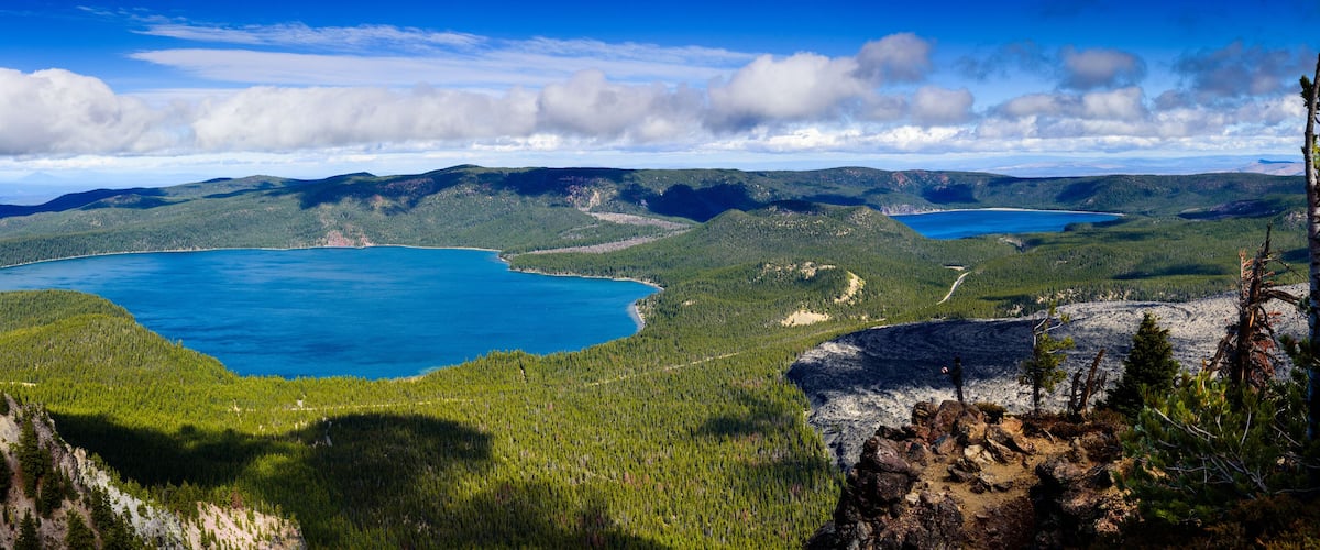 A mountainous landscape with two large turquoise lakes surrounded by dense forests.
