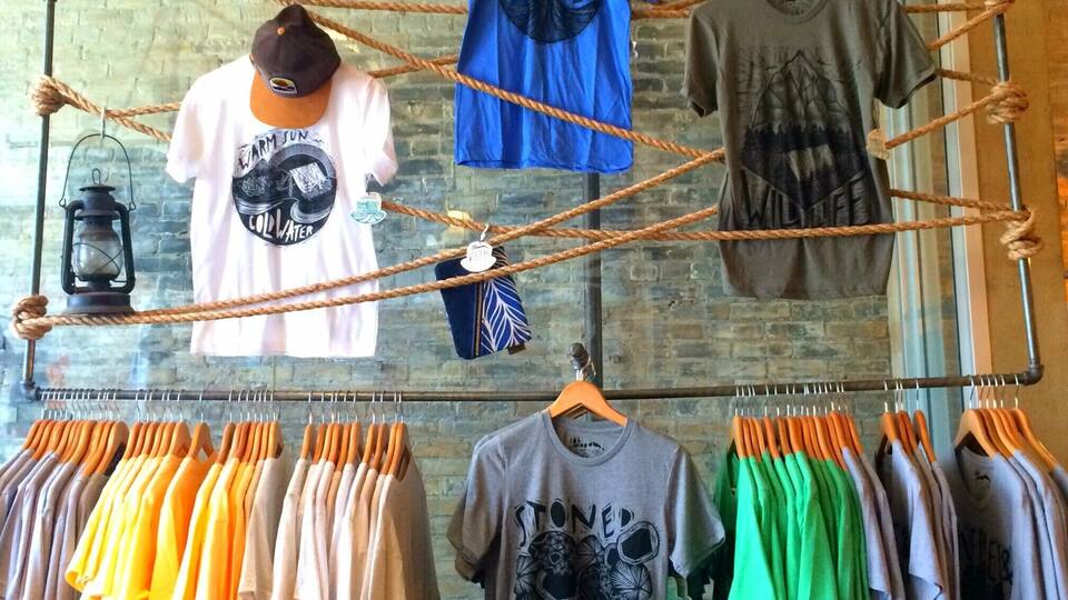 A clothing store with racks of t-shirts and hats.