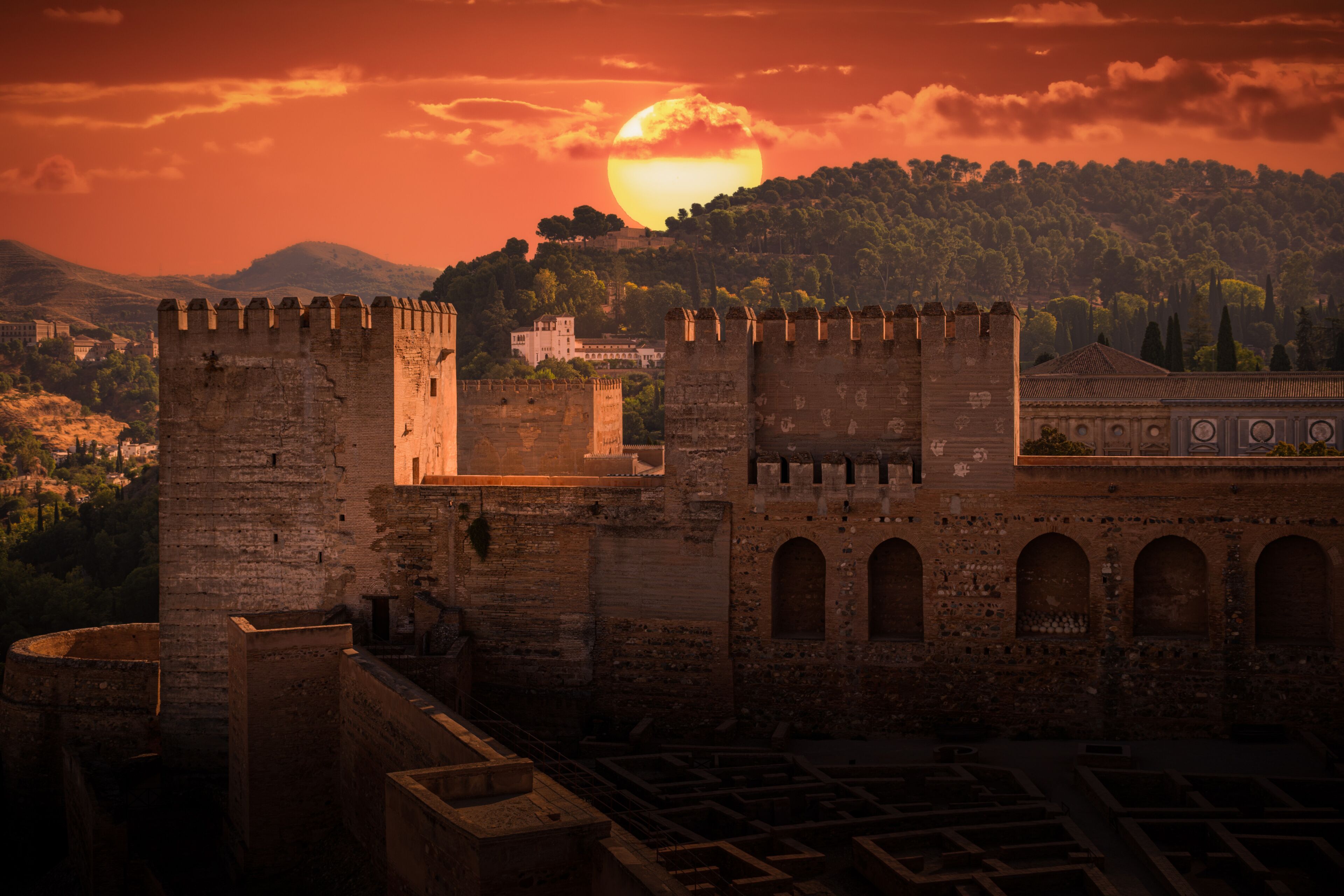 Historic view of the Alhambra and Generalife at sunset with dramatic clouds over the hillside in Granada, Spain