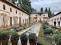 A historic courtyard with a water channel, potted plants, and traditional architecture.