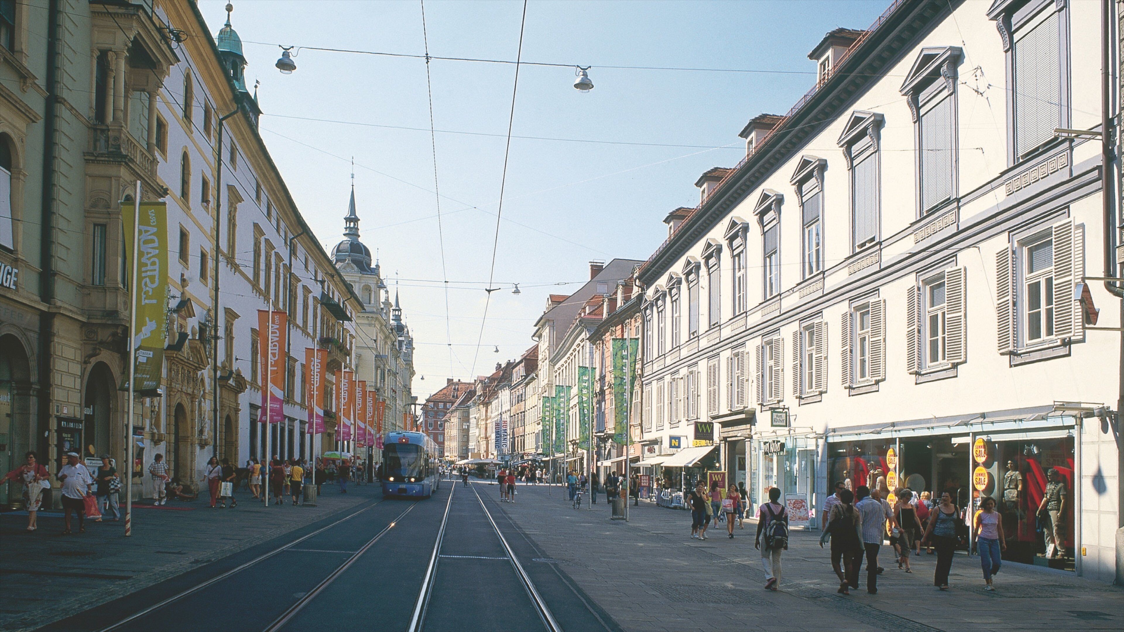 A tram on a street with buildings and people.