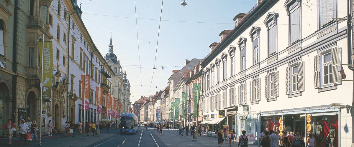 A tram on a street with buildings and people.