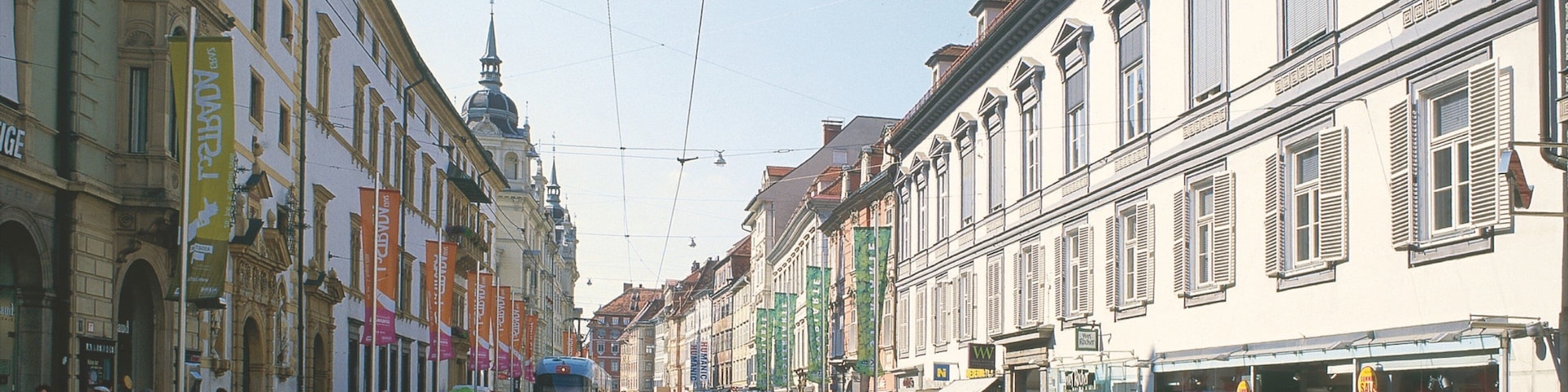 A tram on a street with buildings and people.