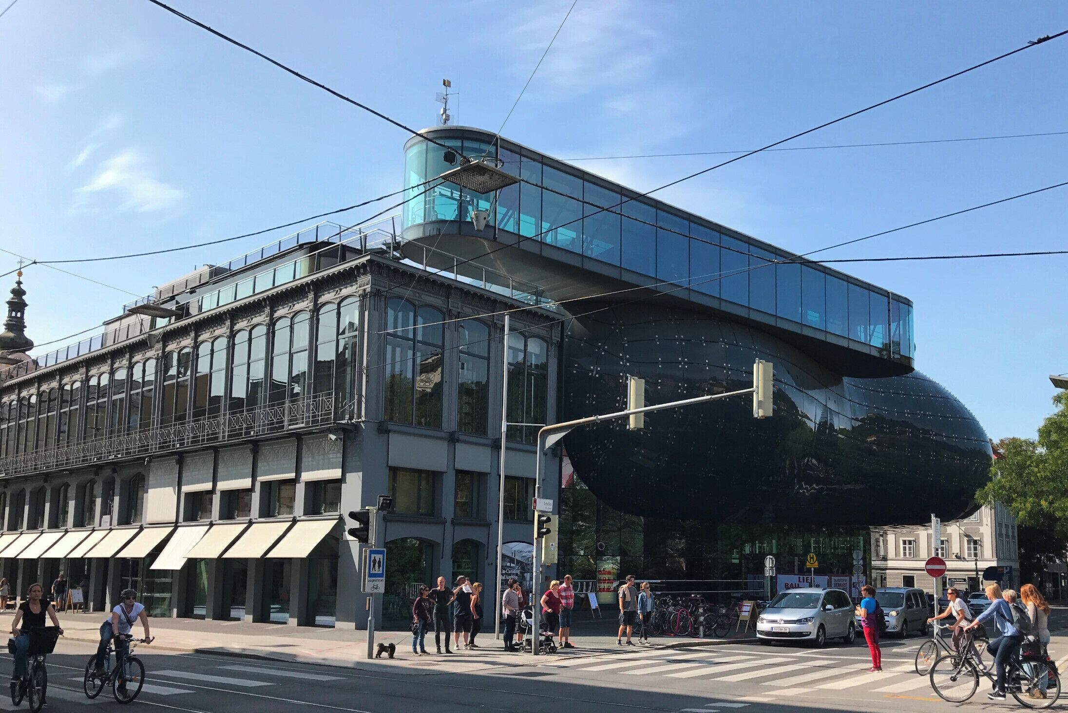 Ein modernes Gebäude mit großen Glasfenstern und einer markanten, kugelförmigen Struktur auf der rechten Seite.