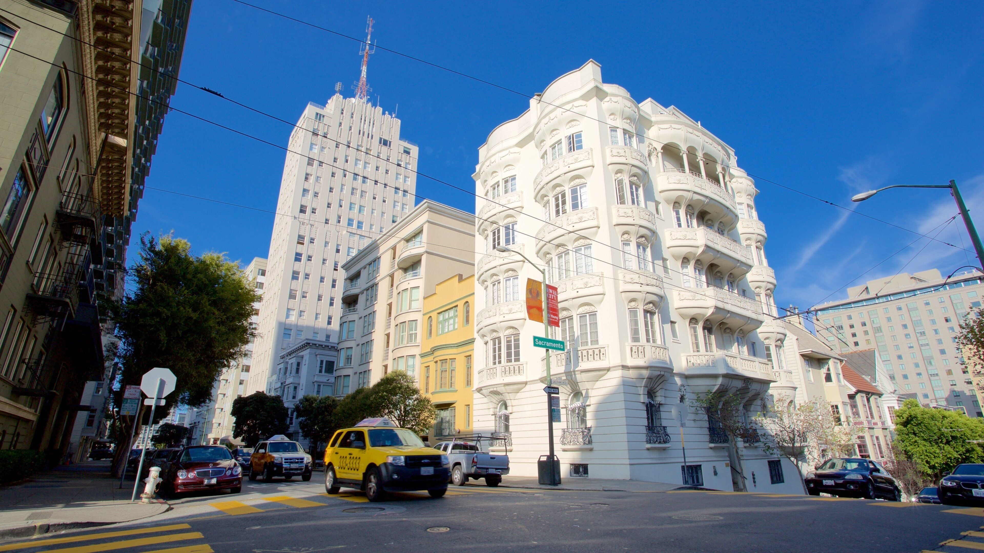 A street with a white building with ornate balconies and a yellow building in the background.