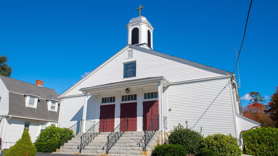 A white church with a steeple and red doors.
