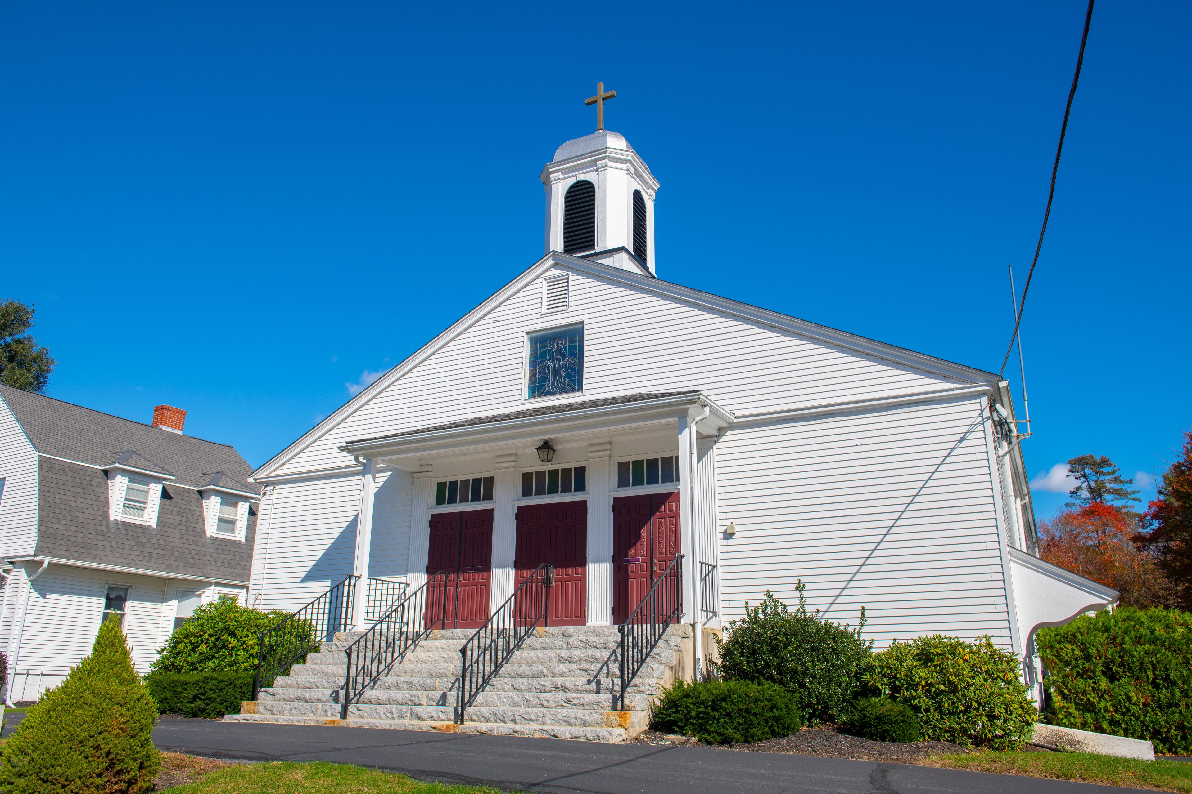 A white church with a steeple and red doors.