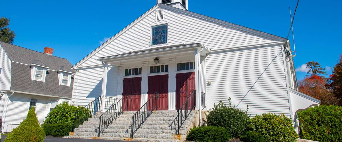 A white church with a steeple and red doors.