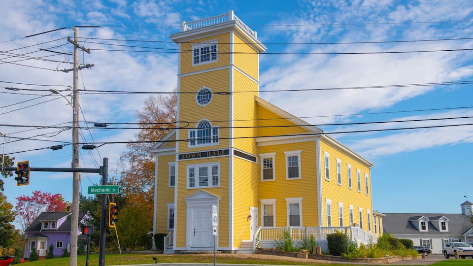 A yellow church with a white steeple and a small bell tower.