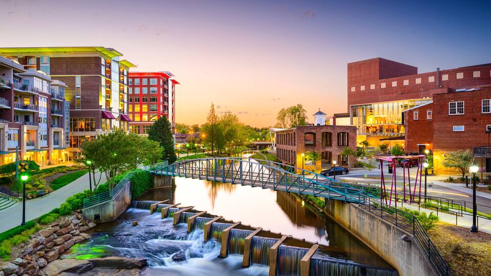 A river with a bridge, buildings, and a waterfall.
