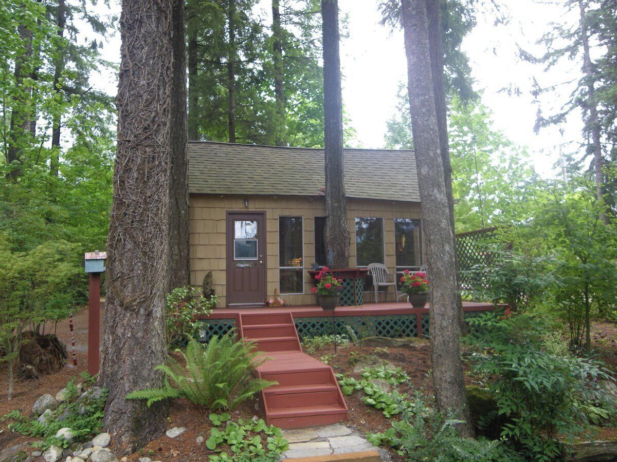 A small house surrounded by trees and a garden.