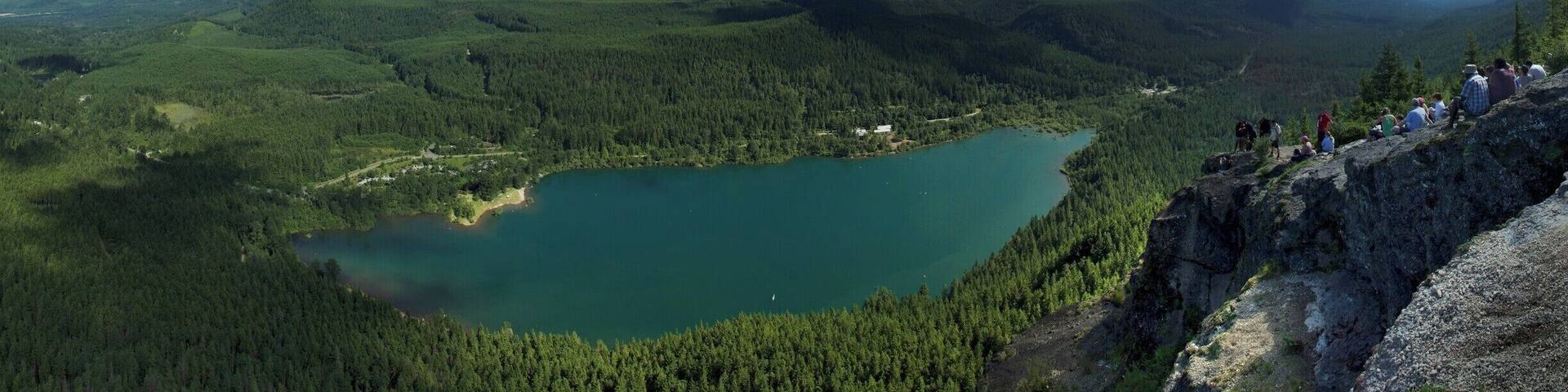 Un lac entouré de montagnes et de forêts denses.